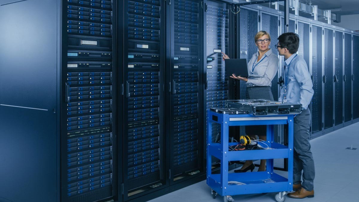 Facilities maintenance technicians reviewing server rack equipment in a data centre