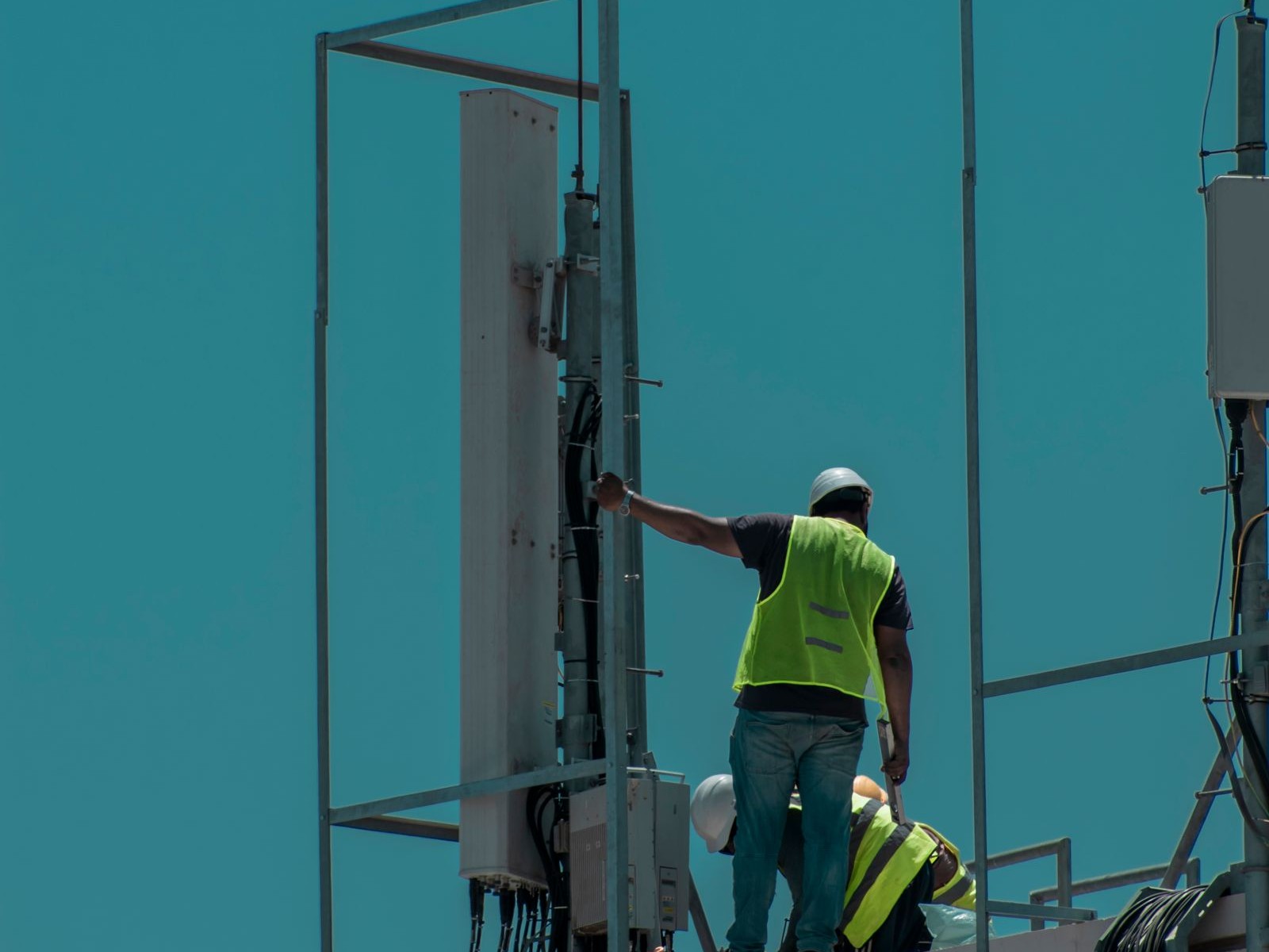 Technicians installing antenna equipment on a rooftop tower