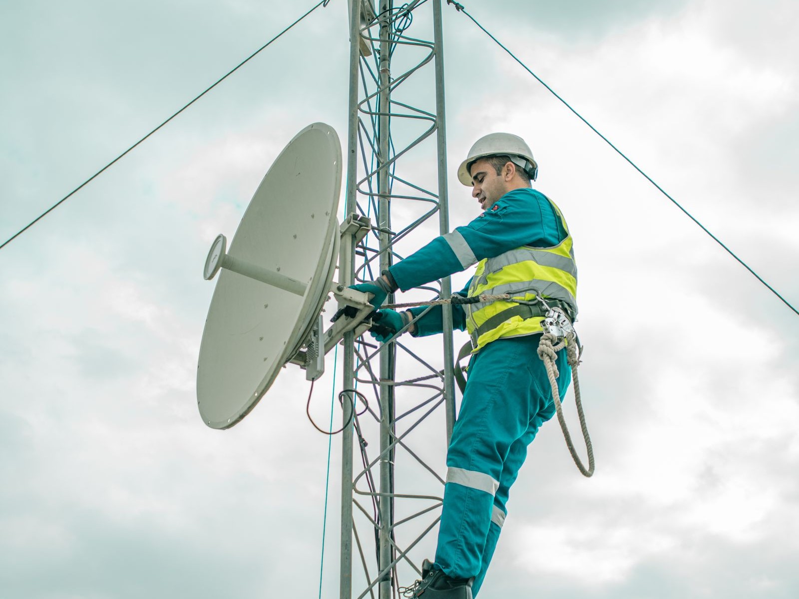 Technician installing a microwave dish on a telecom tower
